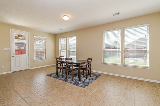 dining space featuring light tile patterned floors, visible vents, and baseboards