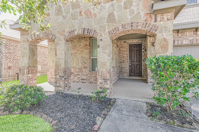 view of exterior entry with stone siding and brick siding