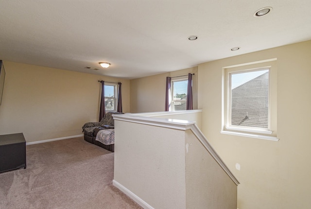 hallway featuring light colored carpet, plenty of natural light, an upstairs landing, and visible vents