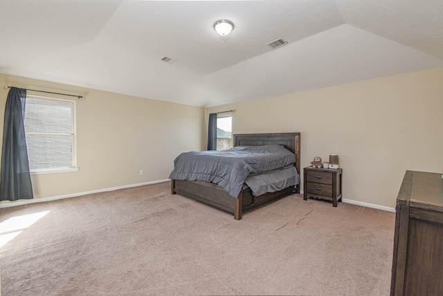 bedroom with visible vents, light colored carpet, a tray ceiling, and baseboards