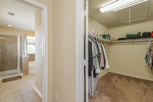 spacious closet with light tile patterned floors, visible vents, and attic access