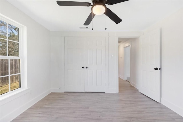 unfurnished bedroom featuring light wood-type flooring, visible vents, a ceiling fan, a closet, and baseboards