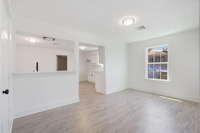 unfurnished room featuring light wood-style flooring, visible vents, and baseboards