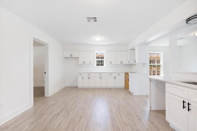 kitchen featuring visible vents, a healthy amount of sunlight, white cabinets, and light wood-style flooring