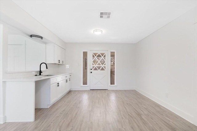 bar featuring a sink, visible vents, baseboards, and light wood-style flooring