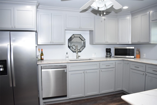 kitchen with a sink, ceiling fan, light stone countertops, appliances with stainless steel finishes, and dark wood-style flooring