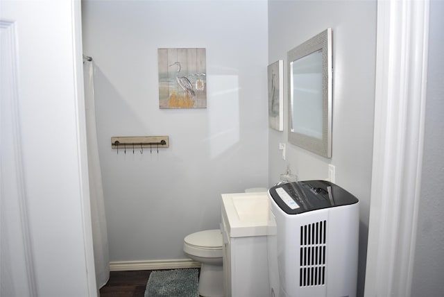 bathroom featuring vanity, toilet, wood finished floors, and baseboards