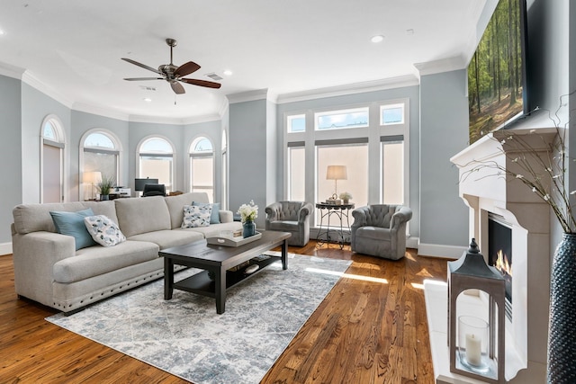 living area with wood finished floors, baseboards, a lit fireplace, and a healthy amount of sunlight