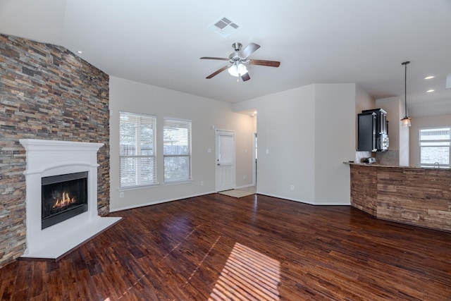 unfurnished living room featuring visible vents, ceiling fan, dark wood finished floors, recessed lighting, and a warm lit fireplace