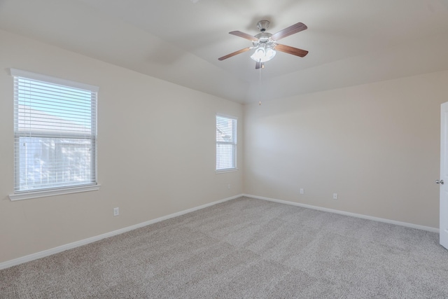 empty room featuring lofted ceiling, a ceiling fan, baseboards, and carpet floors