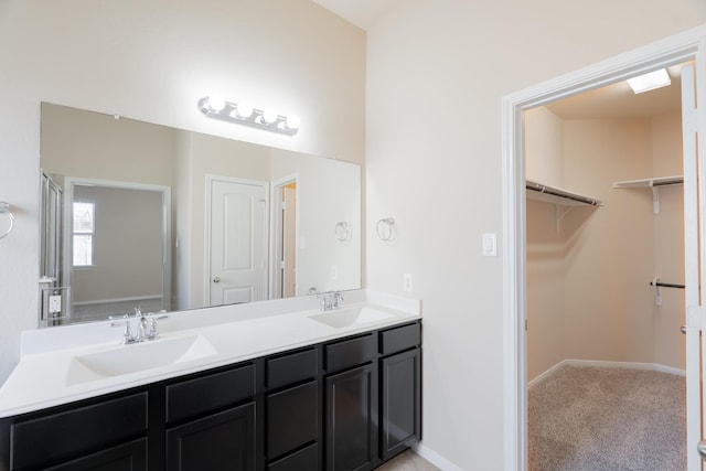 full bath with a sink, baseboards, a spacious closet, and double vanity