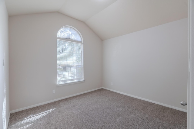 unfurnished room with baseboards, lofted ceiling, and carpet floors