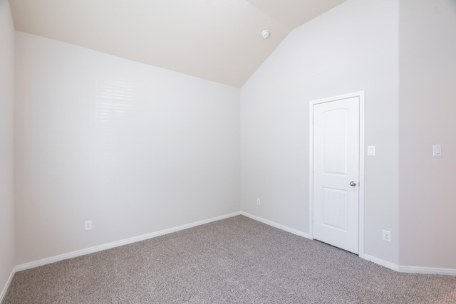 carpeted empty room with baseboards and vaulted ceiling