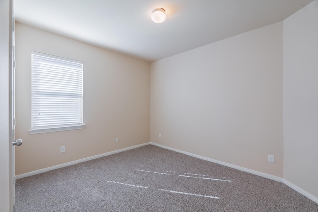 carpeted spare room featuring baseboards