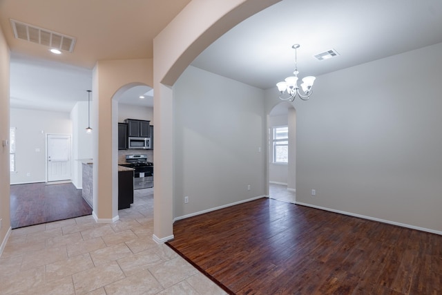 empty room with visible vents, light wood-style flooring, and baseboards