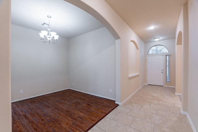 entryway with visible vents, baseboards, arched walkways, and a chandelier