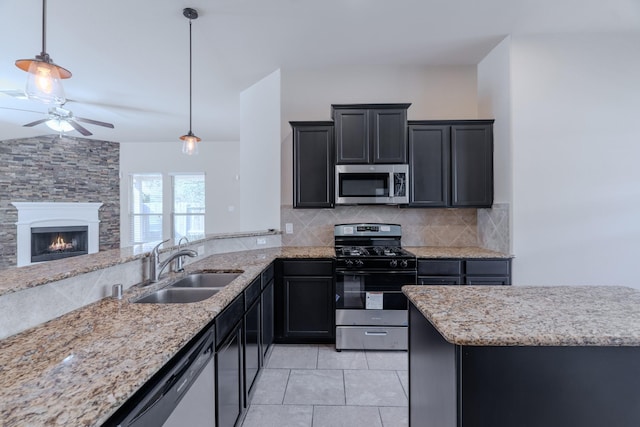 kitchen featuring a ceiling fan, a sink, light stone counters, tasteful backsplash, and appliances with stainless steel finishes