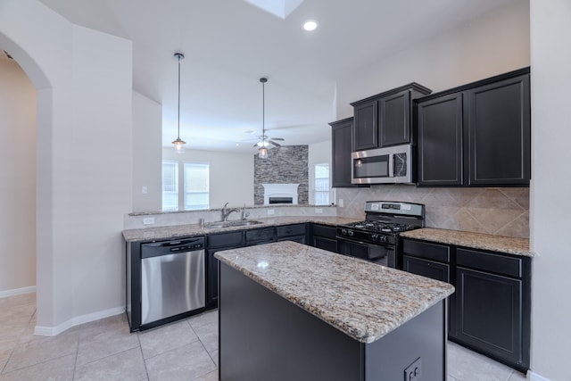 kitchen featuring a sink, a center island, stainless steel appliances, arched walkways, and ceiling fan