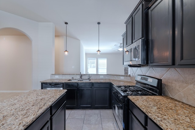 kitchen with backsplash, light stone counters, hanging light fixtures, stainless steel appliances, and a sink