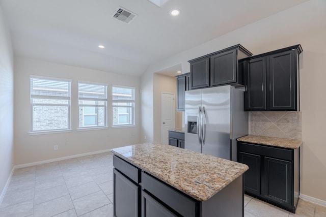 kitchen featuring visible vents, a kitchen island, light stone counters, decorative backsplash, and stainless steel refrigerator with ice dispenser