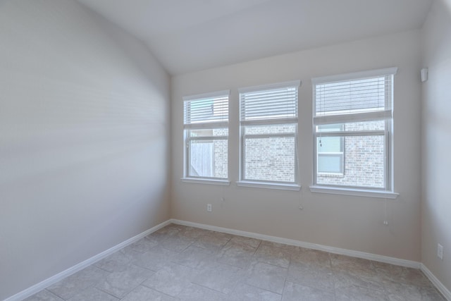 empty room with vaulted ceiling and baseboards