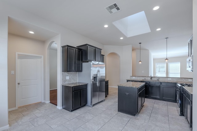 kitchen with visible vents, arched walkways, appliances with stainless steel finishes, and light stone countertops