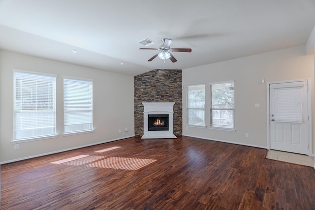 unfurnished living room with visible vents, lofted ceiling, a stone fireplace, wood finished floors, and a ceiling fan