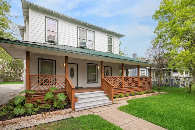 view of front of house featuring a front yard, cooling unit, fence, a porch, and metal roof