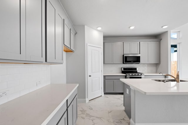 kitchen with marble finish floor, gray cabinetry, a sink, appliances with stainless steel finishes, and light countertops