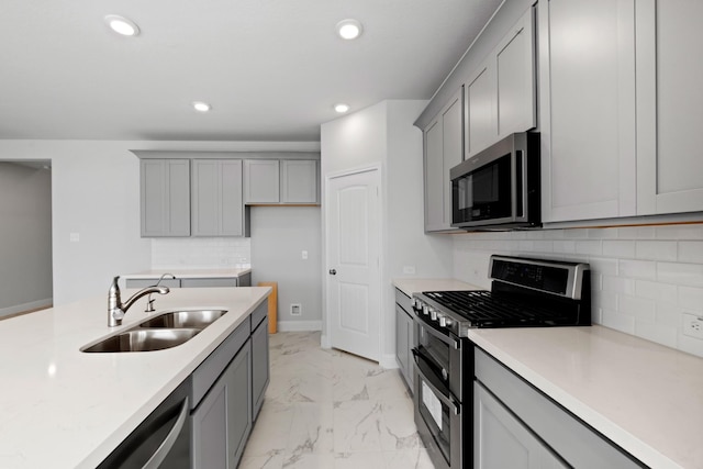 kitchen with recessed lighting, gray cabinets, a sink, appliances with stainless steel finishes, and marble finish floor