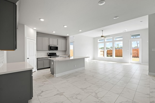 kitchen featuring marble finish floor, gray cabinets, tasteful backsplash, stainless steel appliances, and light countertops