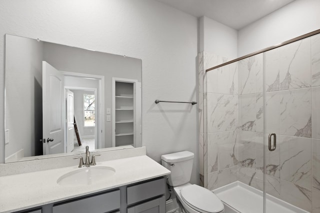 bathroom featuring vanity, a shower stall, and toilet