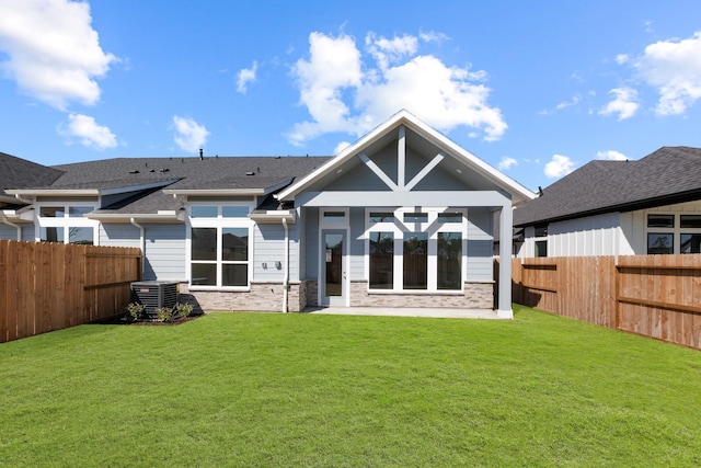 rear view of property with a yard, central air condition unit, and a fenced backyard