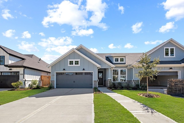 view of front facade featuring board and batten siding, a shingled roof, a front lawn, concrete driveway, and stone siding