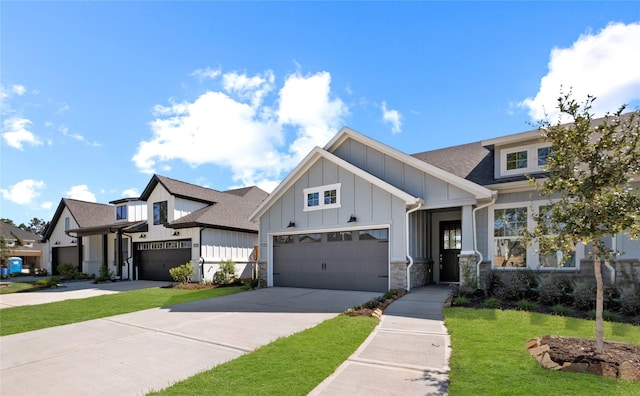 view of front of property featuring driveway, a front lawn, stone siding, roof with shingles, and board and batten siding