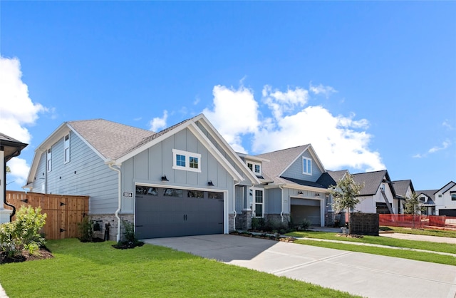 view of front of house with stone siding, fence, board and batten siding, concrete driveway, and a front yard