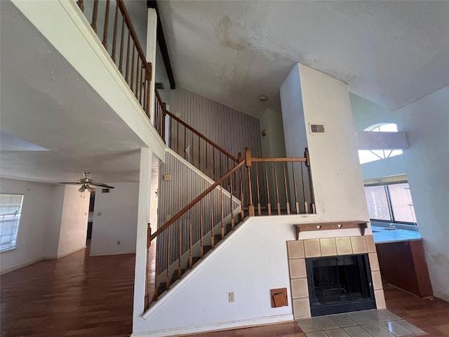 stairway with a wealth of natural light, visible vents, wood finished floors, and a towering ceiling