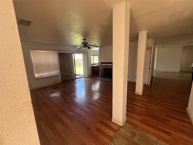 unfurnished living room featuring a ceiling fan, wood finished floors, a textured wall, and a fireplace