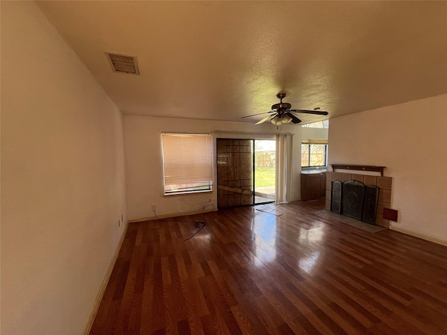 unfurnished living room with visible vents, baseboards, a tiled fireplace, wood finished floors, and a ceiling fan