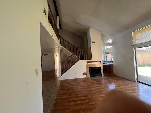 unfurnished living room featuring stairs, wood finished floors, a towering ceiling, and a fireplace