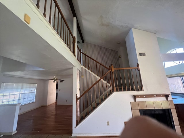 stairs featuring visible vents, a high ceiling, wood finished floors, and a ceiling fan