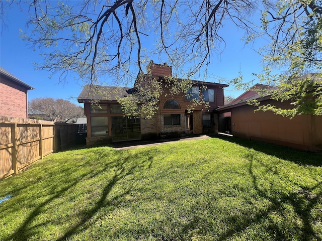 back of property featuring a fenced backyard, a lawn, and a chimney