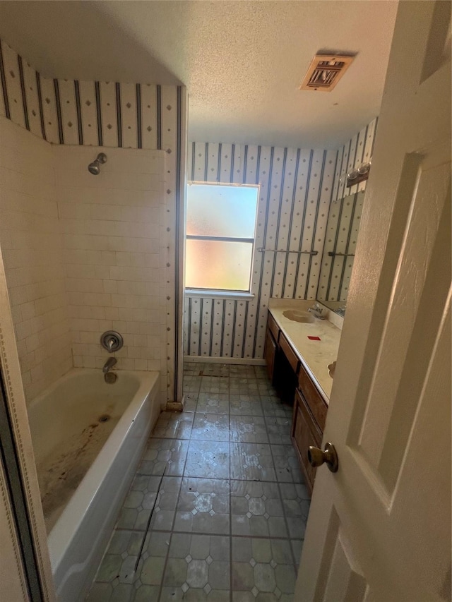 full bathroom featuring visible vents, a textured ceiling, wallpapered walls, baseboards, and vanity