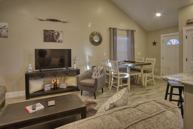 living area with light wood-type flooring, baseboards, and vaulted ceiling