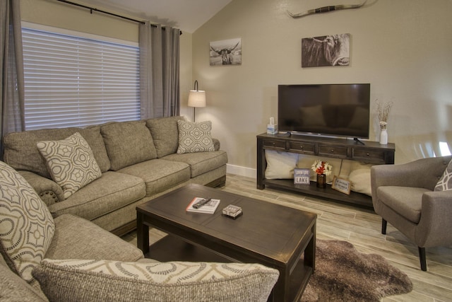 living area featuring vaulted ceiling, baseboards, and wood finished floors