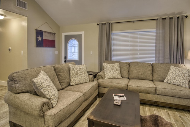 living room with light wood finished floors, visible vents, and lofted ceiling