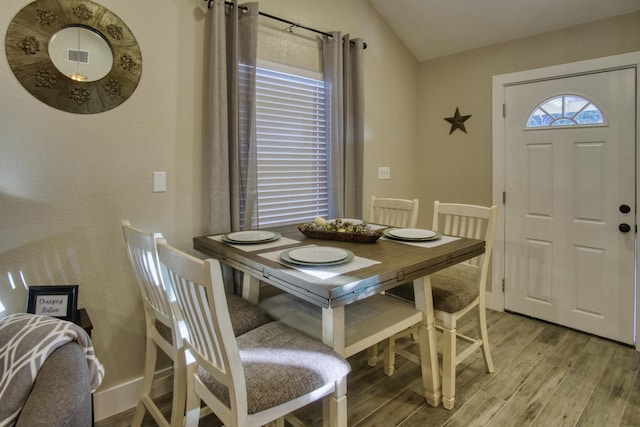 dining space with lofted ceiling, baseboards, and light wood finished floors