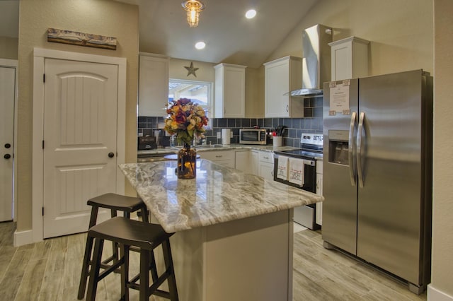 kitchen featuring decorative backsplash, wall chimney range hood, light wood-style flooring, and appliances with stainless steel finishes