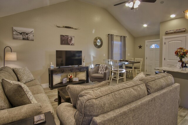 living area featuring high vaulted ceiling, baseboards, light wood-style floors, and a ceiling fan