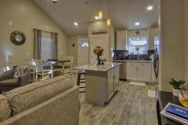 kitchen with light wood finished floors, a kitchen island, white cabinets, and stainless steel appliances